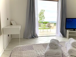 Una habitación de hotel con cama, escritorio, televisor y vistas al exterior.