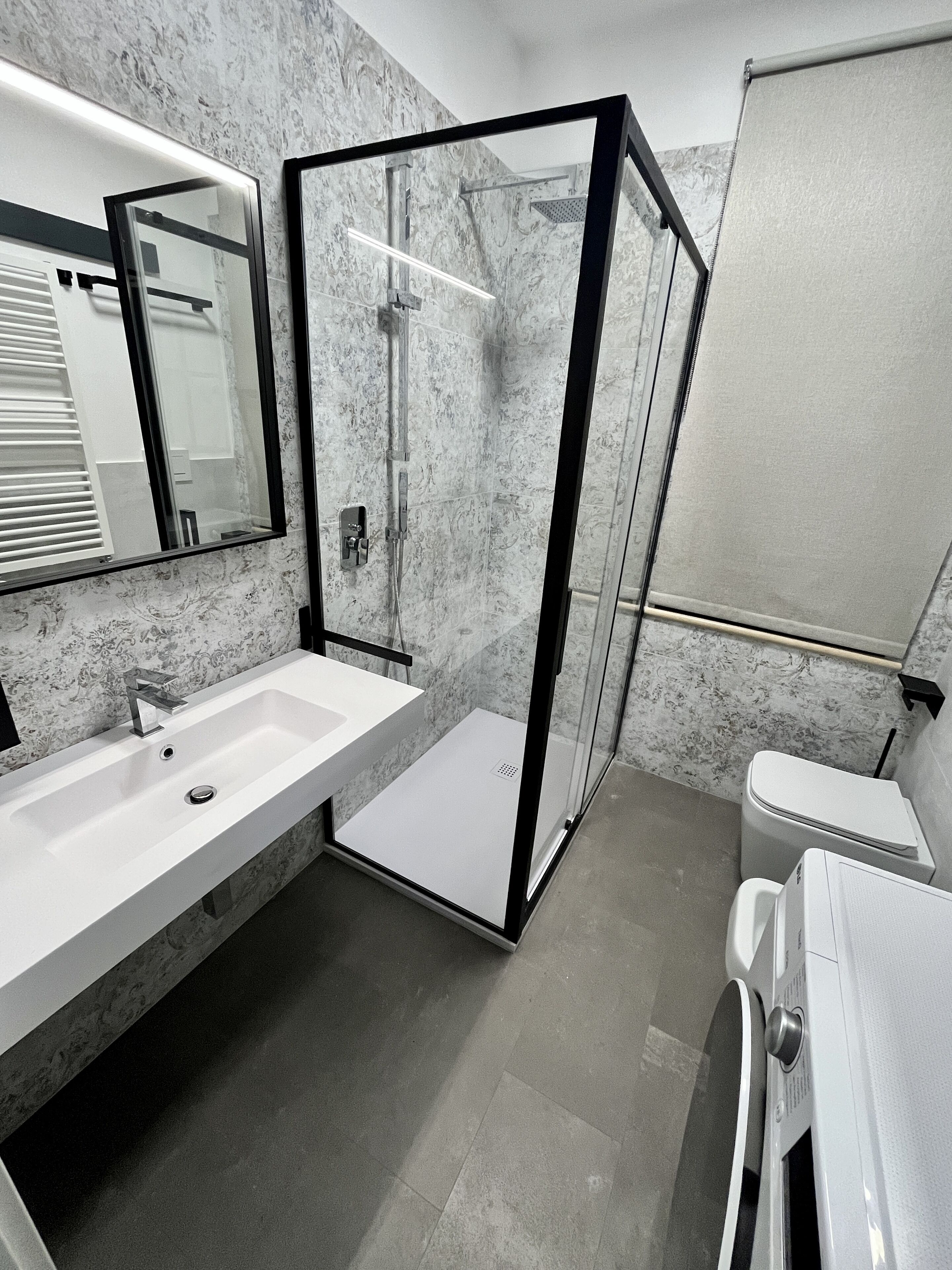 A modern bathroom with a glass-enclosed shower, a large sink, and a toilet.