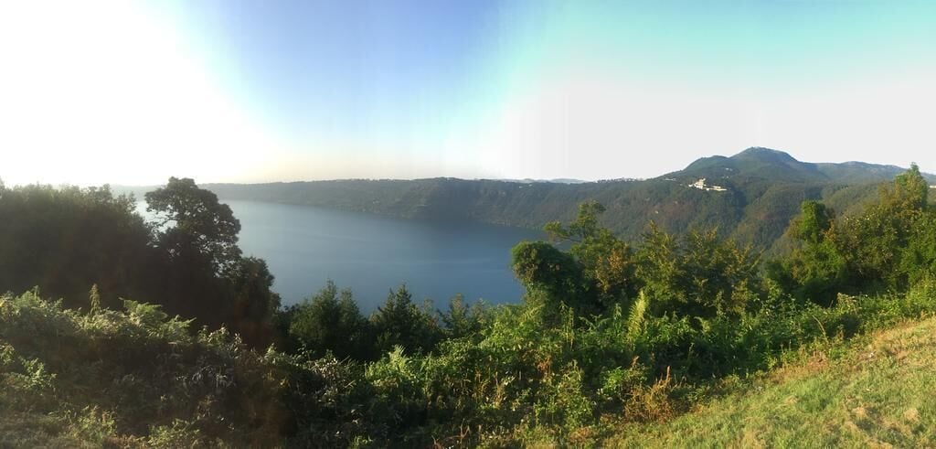 A lake surrounded by hills and dense greenery.