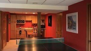 A ping pong table in a room with a kitchen area visible through an open door. - Rock River Haven - charming, spacious, peaceful (Watertown)