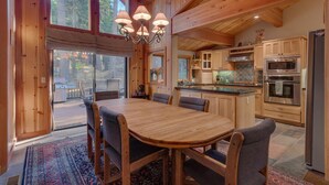 Ein Holzblockhaus-Interieur mit Essbereich, Küche und großen Fenstern.