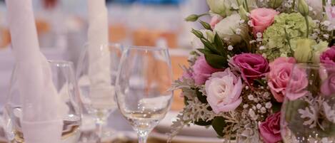 A table set for a formal event with white napkins, clear wine glasses, and a floral centerpiece.