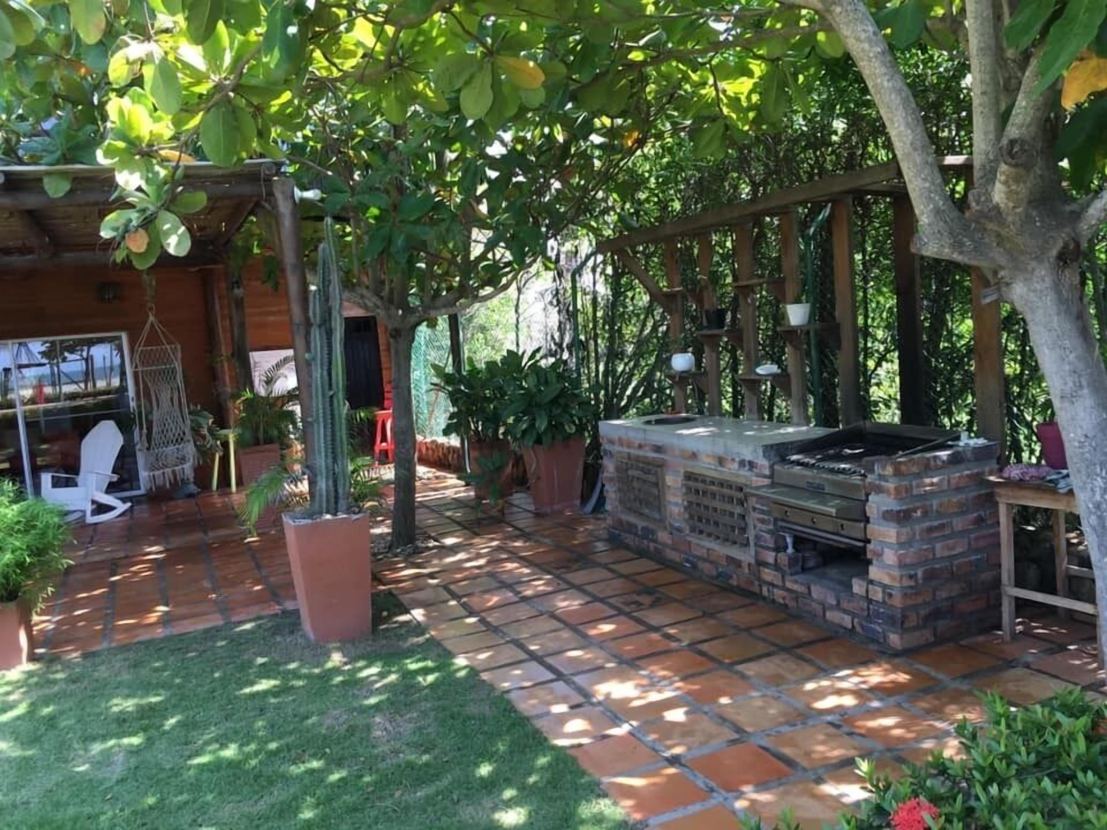 A patio area with a brick barbecue, potted plants, and a hanging chair.