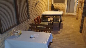 An outdoor patio with a table and chairs, a brick wall, and a door. - Citadela - Large Double Room (Sombor)