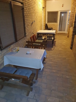 Patio esterno con tavolo e sedie, un muro in mattoni e una porta.