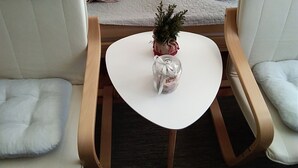 A cozy seating area with a small table, a decorative plant, and a glass jar with a ribbon. - Citadela - Large Double Room (Sombor)