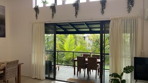 A room with a sliding glass door leading to a balcony with wicker furniture and a TV. - Baden 86 - Rainbow Shores. Walk To Beach - Top Floor - Air conditioned Unit. Free Wi-Fi (RAINBOW BEACH)