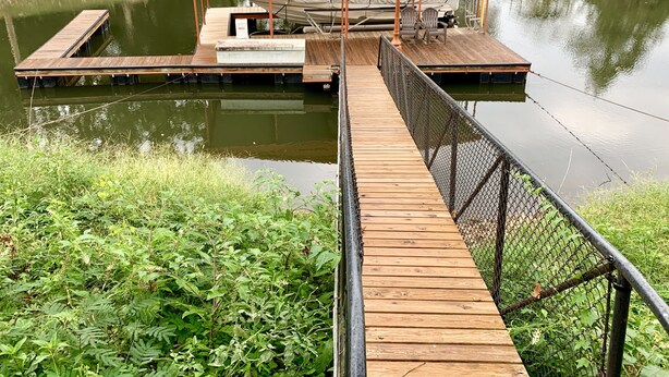 Un muelle de madera que conduce a un espacio de descanso cubierto con un bote.
