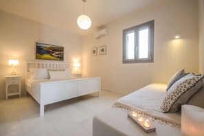 A bedroom with a bed, bedside tables, a painting, and a window.