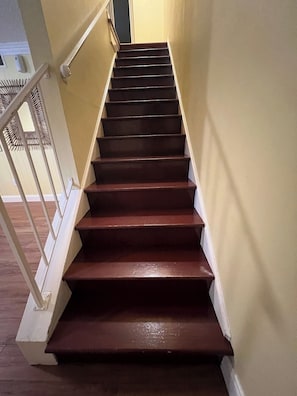 Eine Holztreppe mit Handlauf, die zu einer Zwischenebene führt.
