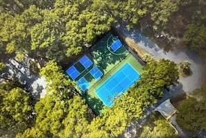 An aerial view of a tennis court surrounded by dense greenery. - On Island Pool, pet friendly, free tennis andparking (Hilton Head Island)