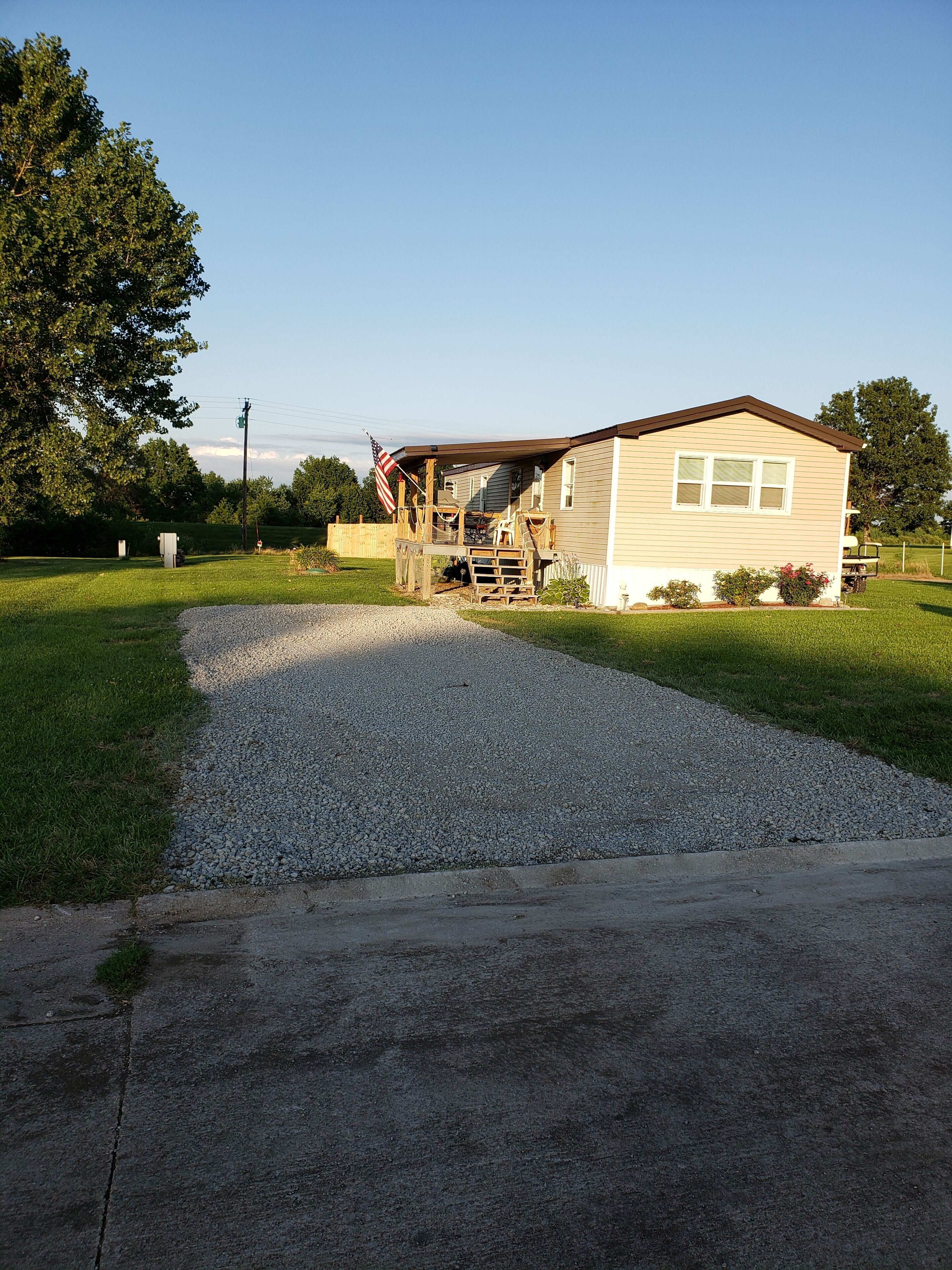 A single-story house with a porch, a gravel driveway, and a lawn.