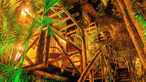 A wooden structure with a spiral staircase surrounded by dense foliage. - Moradas do Vale Praia do Rosa (Imbituba)
