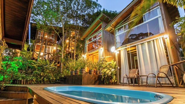 A wooden deck with a swimming pool, surrounded by potted plants and a wooden fence. - Moradas do Vale Praia do Rosa (Imbituba)