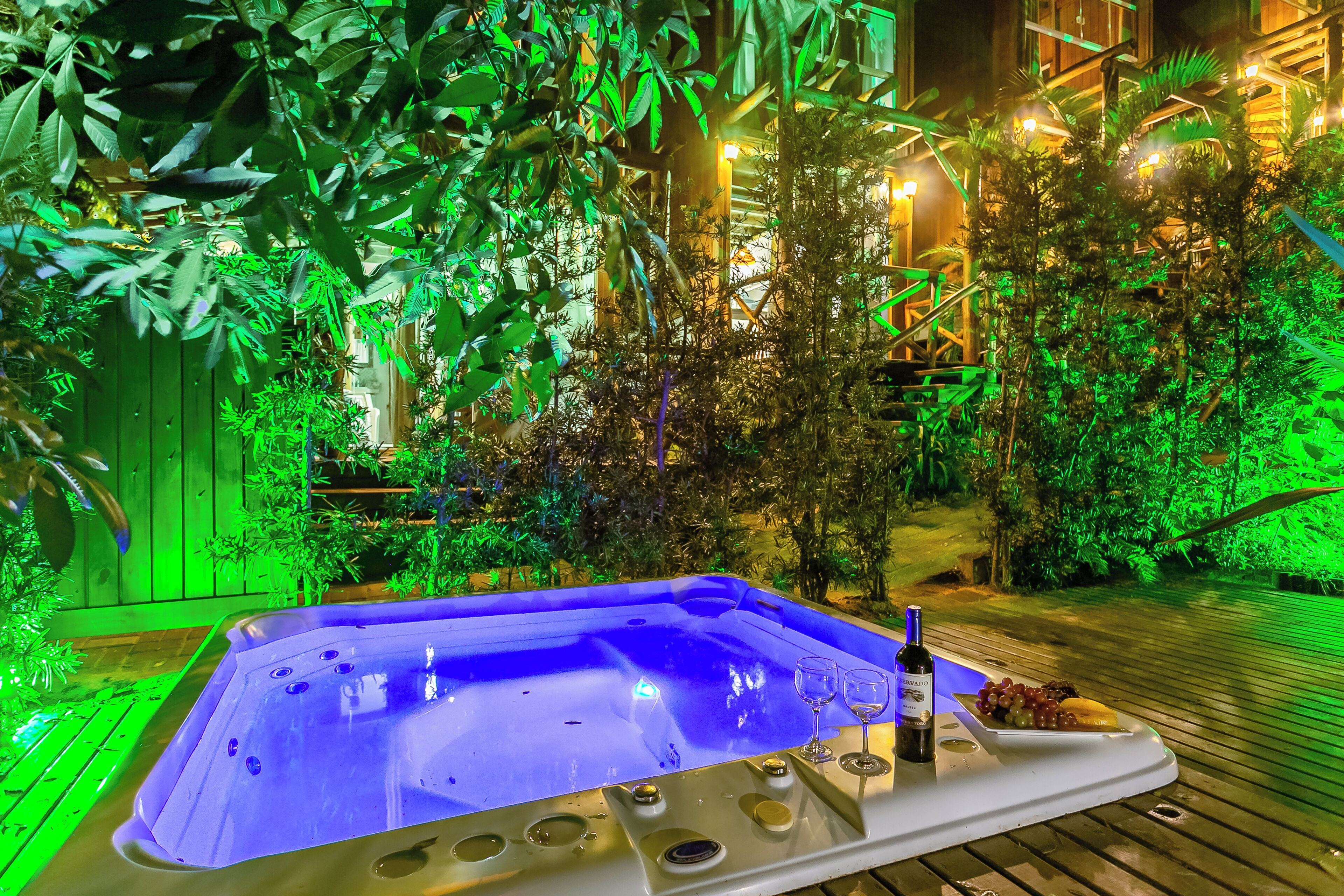 A hot tub surrounded by lush greenery and wooden decking.