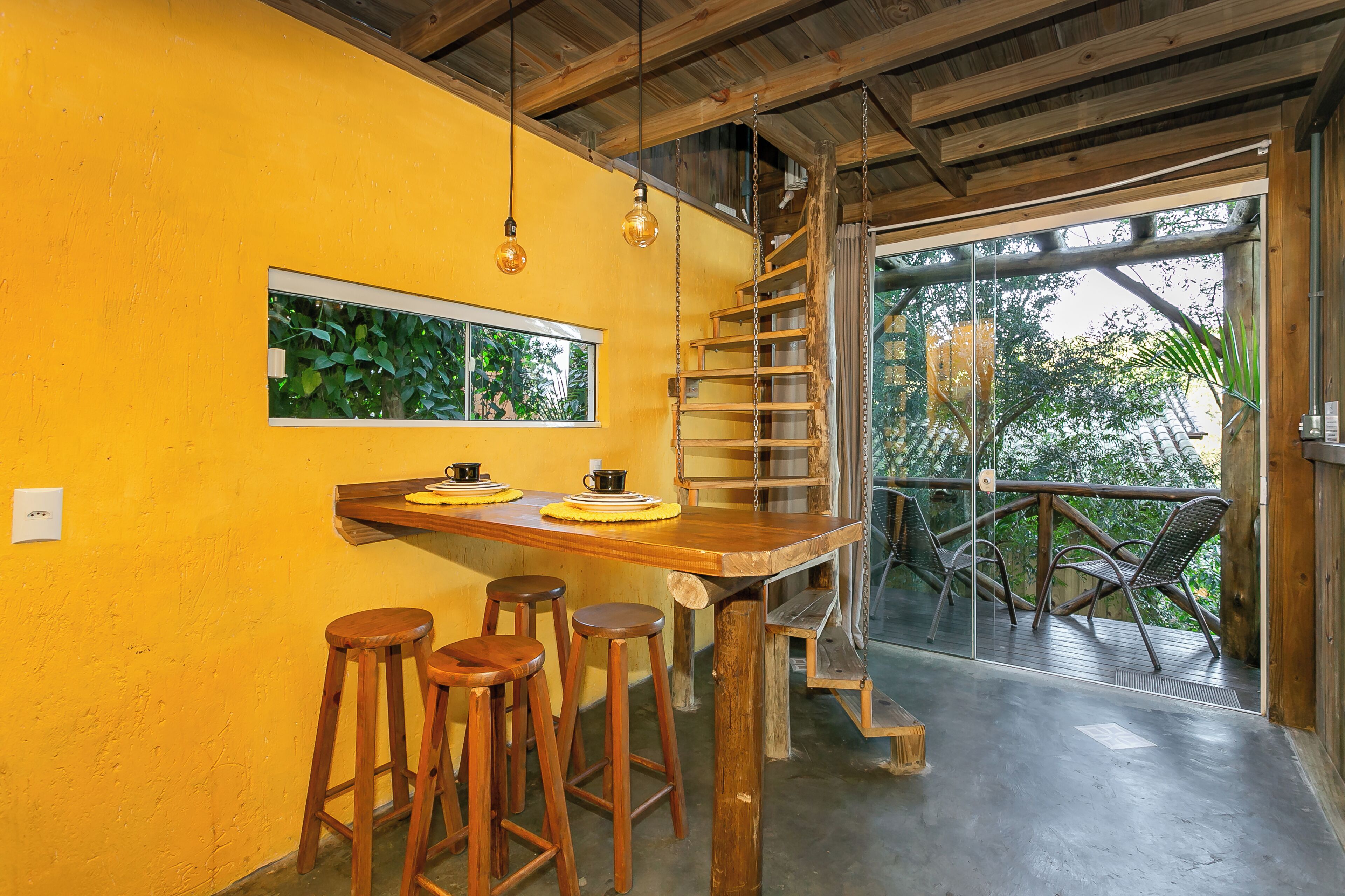 Una escalera de madera que conduce a un balcón con mobiliario para exteriores.