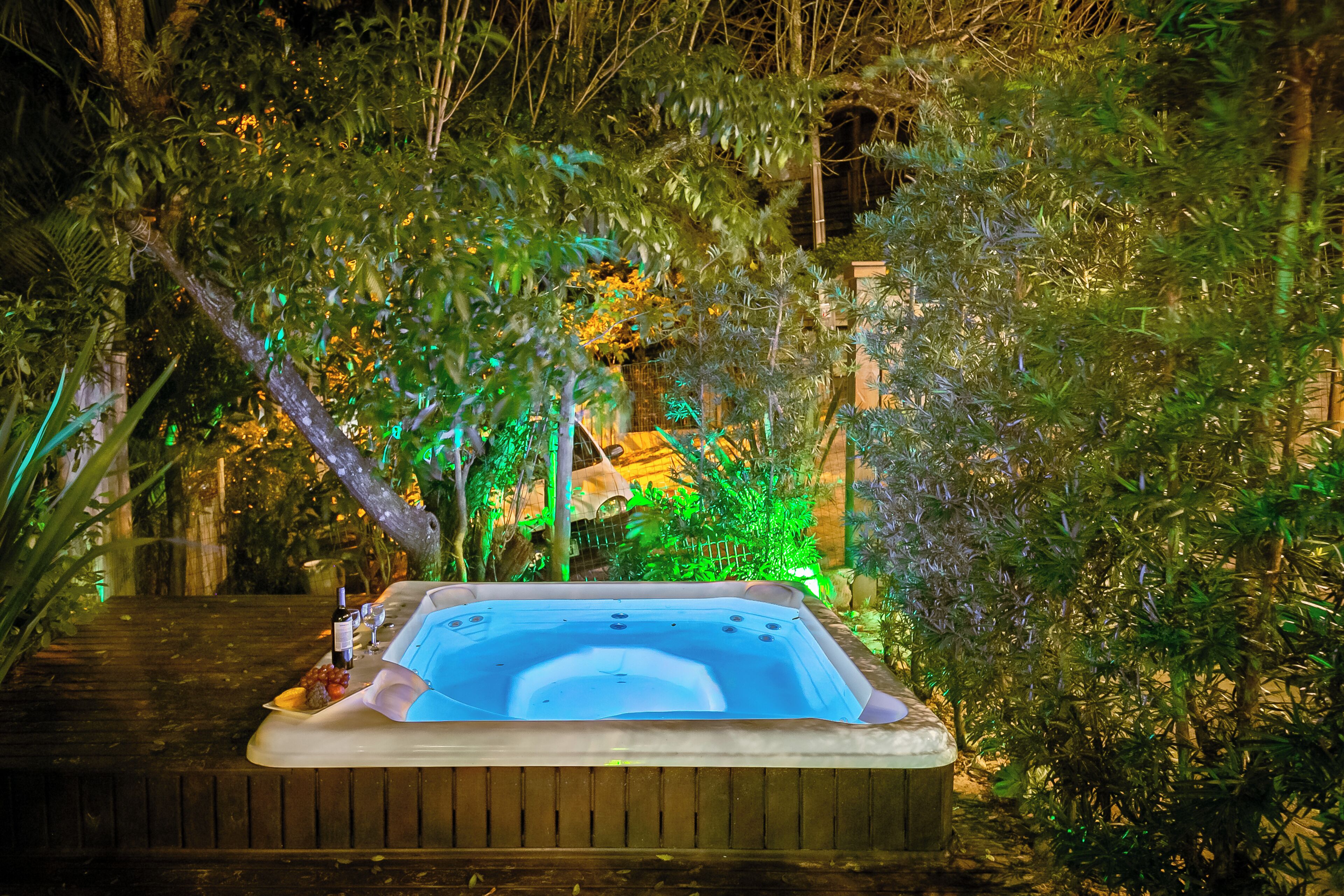 A hot tub surrounded by lush greenery and a wooden deck.