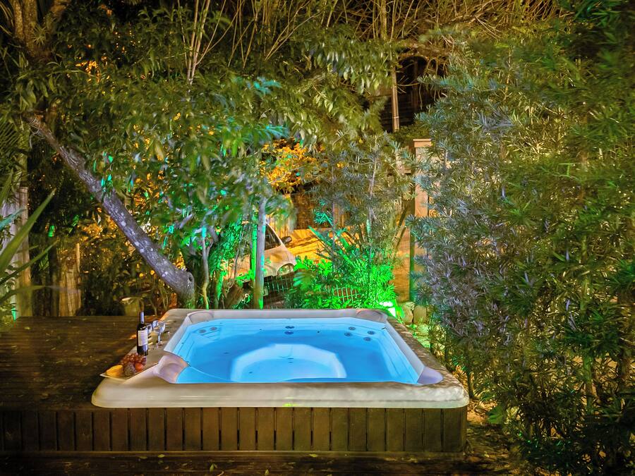 A hot tub surrounded by lush greenery and a wooden deck.