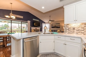 Enjoy cooking in this well-lit kitchen with a large island, dishwasher, and white cabinetry.