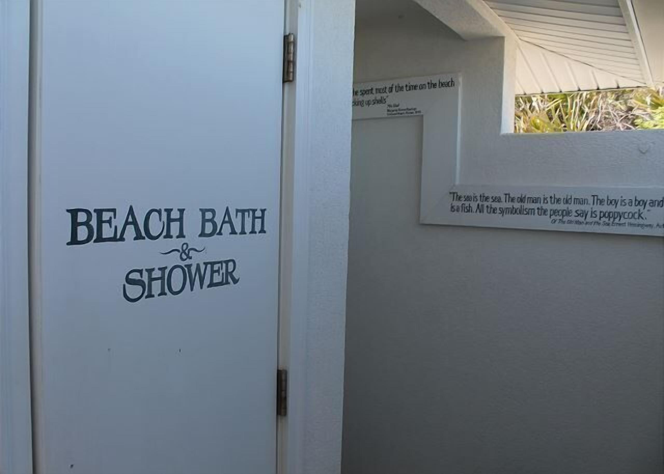 A door labeled 'BEACH BATH & SHOWER' with a quote on the wall above it.