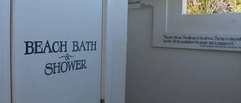 A door labeled 'BEACH BATH & SHOWER' with a quote on the wall above it.