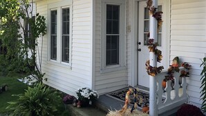 A white house with a porch decorated with autumn leaves and a small pumpkin. - Aiken Manor B&B (Franklin)