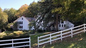A white house with a front porch, surrounded by trees and a white fence. - Aiken Manor B&B (Franklin)
