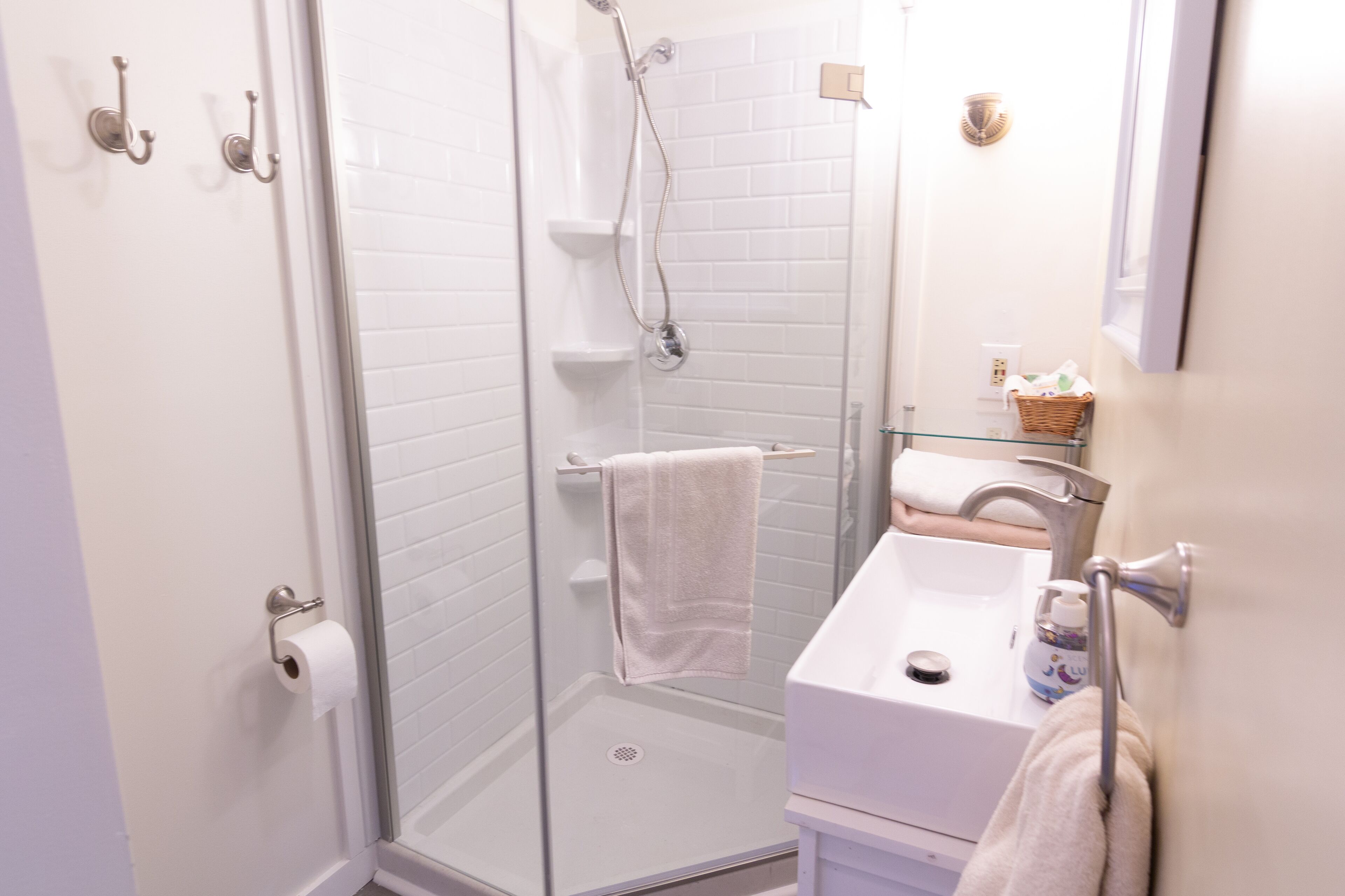 A modern bathroom with a glass-enclosed shower, a white sink, and a mirror.
