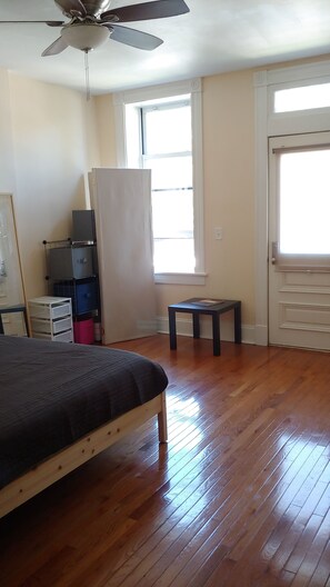 A bedroom with a bed, a ceiling fan, a window, and a door.