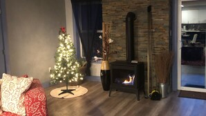 Un salon avec une cheminée, un sapin de Noël et un canapé rouge.