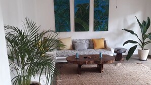 Uma sala de estar com sofá, mesa de centro e plantas em vasos grandes.