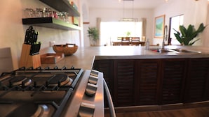 Uma cozinha com fogão a gás, armários de madeira e um espaço de jantar com mesa e cadeiras.