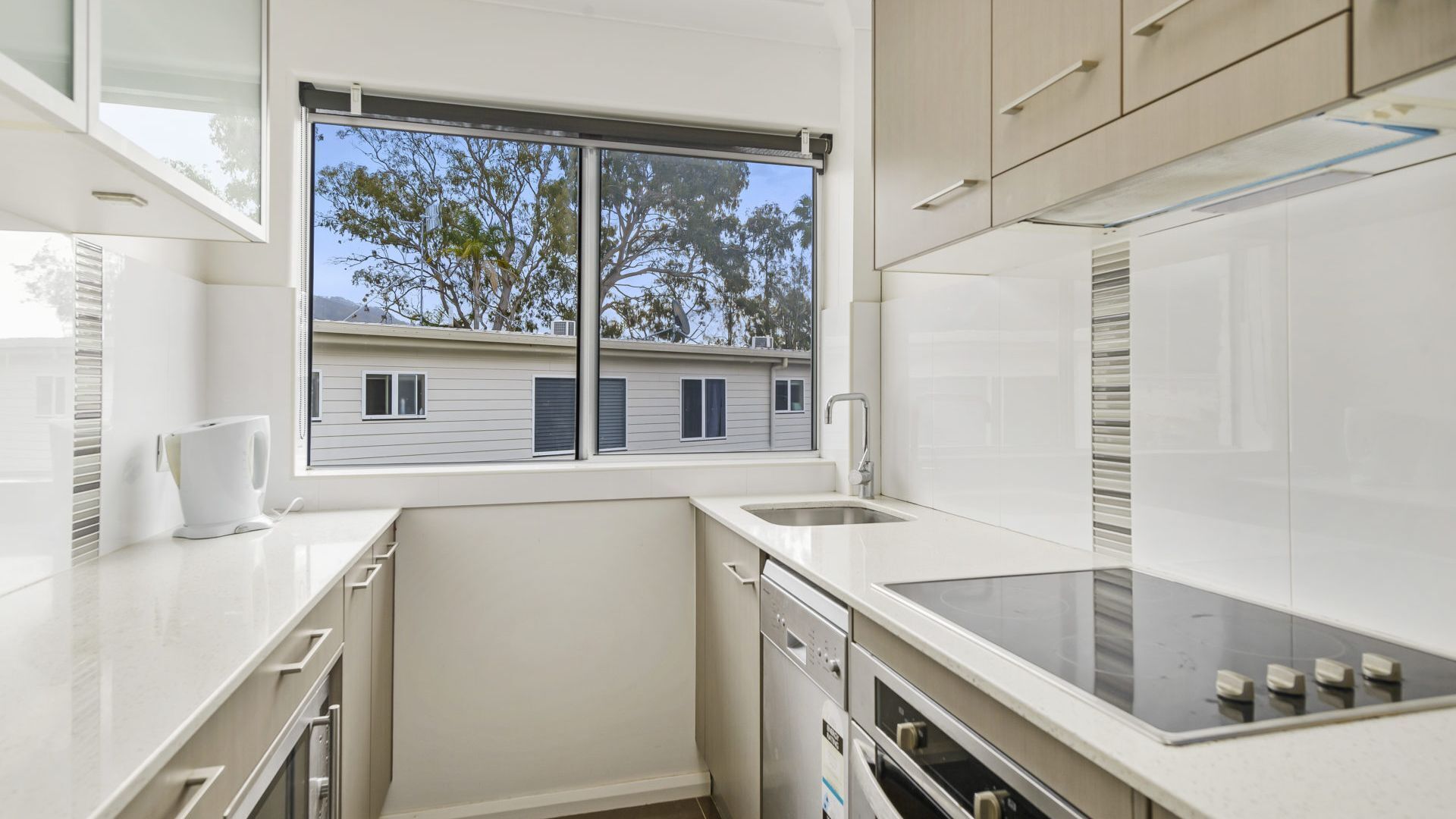 A compact kitchen with a window, white cabinetry, and a dishwasher.