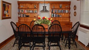 A dining room with a wooden table, black chairs, a floral centerpiece, and bookshelves. - Ocean Block Rehoboth Beach House Sleeps 10 (Rehoboth Beach)