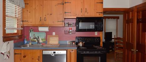 A kitchen with wooden cabinets, a dishwasher, a stove, and a microwave.