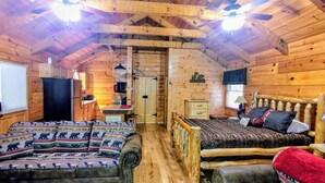 A cozy log cabin interior with a sofa, a bed, a dining area, and a kitchen. - Newly updated cabin, 10 min to pkwy in Pigeon Forge. Screen porch, hot tub,WiFi. (Sevierville)