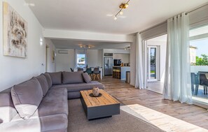 A modern living room with a sofa, a coffee table, and a dining area in the background.