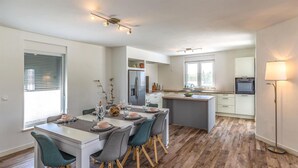 Eine moderne Küche mit einer zentralen Kochinsel, eingebauten Geräten und einem Essbereich mit Tisch und Stühlen.