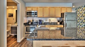 A modern kitchen with wooden cabinets, stainless steel appliances, and a granite countertop.
