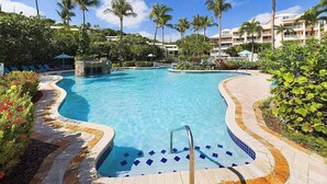 A clear blue pool with a stone edge, surrounded by palm trees and a landscaped garden. - Cowpet Bay Beach Front Villa with Amazing Views (Elysian Beach Resort)