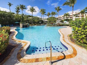 A clear blue pool with a stone edge, surrounded by palm trees and a landscaped garden. - Cowpet Bay Beach Front Villa with Amazing Views (Elysian Beach Resort)