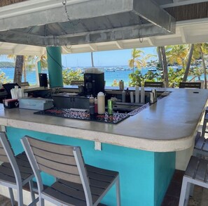 An outdoor bar area with a view of the ocean, equipped with bar stools and a coffee machine. - Cowpet Bay Beach Front Villa with Amazing Views (Elysian Beach Resort)