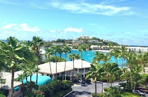A resort with a large pool, palm trees, and buildings on a hillside. - Cowpet Bay Beach Front Villa with Amazing Views (Elysian Beach Resort)