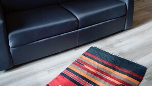A dark-colored sofa against a white wall with a framed picture of the Eiffel Tower. - Studio l'Orchidée Mobility lease (1 to 10 months) (Rueil-Malmaison)
