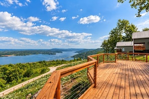Une terrasse en bois offrant une vue sur un lac et des collines.