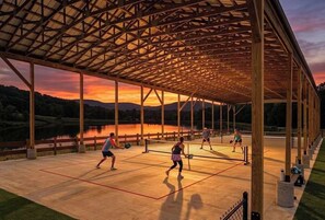En udendørs tennisbane med en pavillon i træ, omgivet af natur.