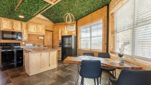 A modern kitchen with wooden cabinets, a central island, and a dining area with chairs.