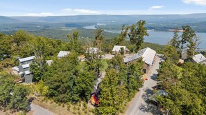 A residential area with houses surrounded by dense trees and a lake in the background. - The Yurt at Paradise Pointe with a hot tub, fire pit, & Grill (Bryant)