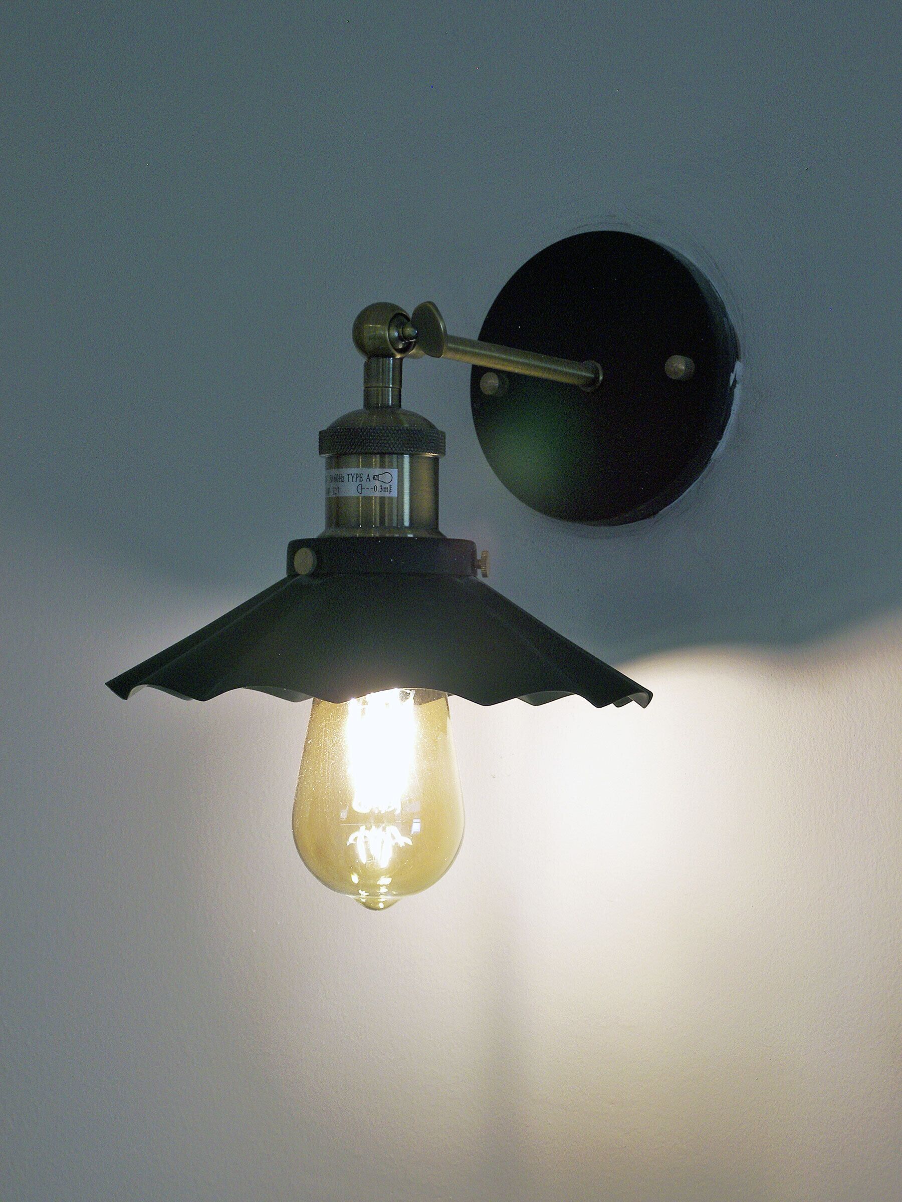 Una lámpara de pared con bombilla de vidrio y base de metal.
