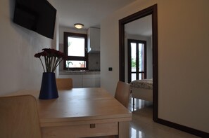 A modern kitchen with white cabinets and a window. There is a dining table with chairs and a vase of flowers. - Flatinrome Fiera 5   private terrace (ROMA)